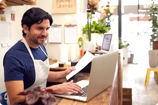Small business professional reviewing work on a laptop in a plant shop